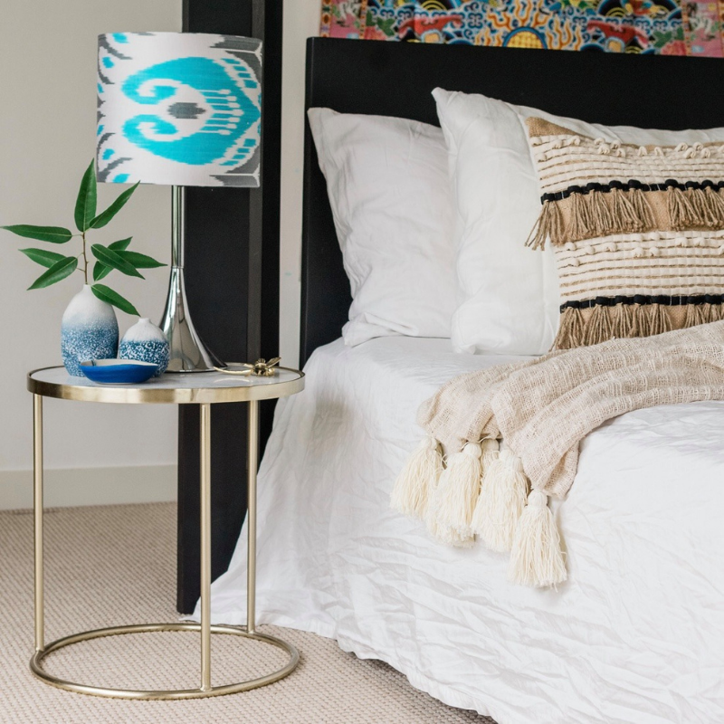 Bed with white linen, bedside table with lamp and decoration